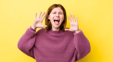 Kızıl saçlı, güzel bir kadın panik ya da öfke içinde bağırıyor, şok olmuş, korkmuş ya da öfkeli, elleri başının yanında.
