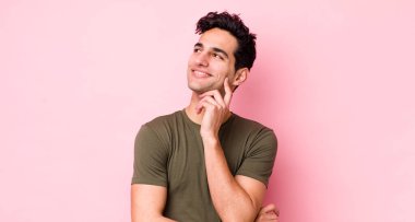 Yakışıklı İspanyol adam mutlu bir şekilde gülümsüyor ve hayal kuruyor ya da şüphe ediyor.