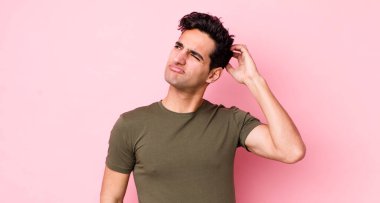 Yakışıklı İspanyol adam şaşkın ve şaşkın hissediyor, başını kaşıyor ve yana bakıyor.