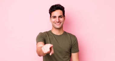 Yakışıklı İspanyol bir adam kameraya bakıyor. Tatmin olmuş, kendine güvenen, dost canlısı bir gülümsemeyle, seni seçiyor.