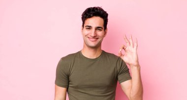 Yakışıklı İspanyol adam kendini mutlu, rahat ve tatmin olmuş hissediyor. Onayını iyi bir hareketle gösteriyor. Gülümsüyor.