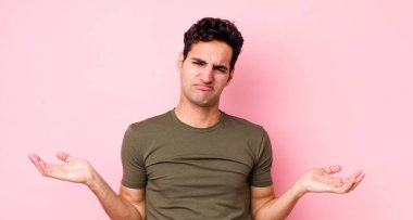 Yakışıklı İspanyol adam şaşkın, kafası karışmış ve stresli görünüyor, farklı seçenekler arasında merak ediyor, kararsız hissediyor.