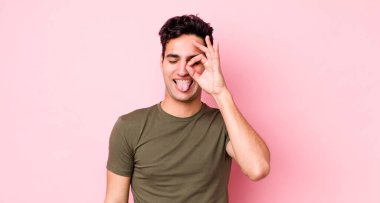 Yakışıklı İspanyol adam mutlu bir şekilde gülümsüyor, şaka yapıyor, gözetleme deliğinden bakıyor, sırları gözetliyor.