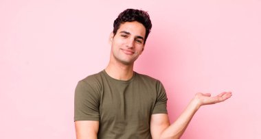 Yakışıklı İspanyol adam gururla ve güvenle gülümsüyor, mutlu ve tatmin olmuş hissediyor ve fotokopi alanında bir konsept gösteriyor.