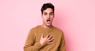 Yakışıklı İspanyol adam şok olmuş, şaşırmış ve şaşırmış hissediyor, elleri göğsünde ve ağzı açık, kim olduğunu söylüyor, ben mi??