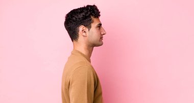 Profil görünümlü yakışıklı İspanyol adam uzayı kopyalamaya çalışıyor, düşünüyor, hayal ediyor ya da hayal kuruyor.