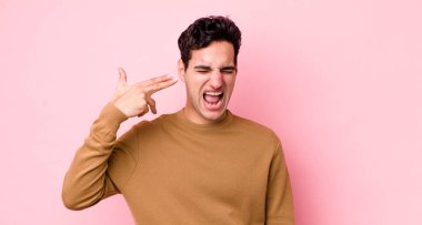 Yakışıklı İspanyol adam mutsuz ve stresli görünüyor, intihar jesti elle silah işareti yapıyor, kafasını işaret ediyor.