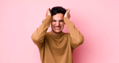 Yakışıklı İspanyol bir adam stresli ve endişeli, depresif ve hayal kırıklığına uğramış hissediyor, iki elini de başa kaldırıyor.