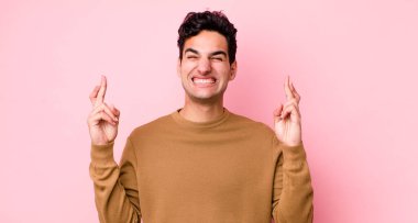 Yakışıklı İspanyol adam gülümsüyor ve endişeyle iki parmağını çapraz yapıyor. Endişeli ve iyi şanslar diliyor.