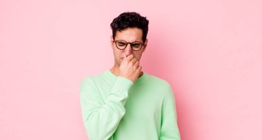 Yakışıklı İspanyol bir adam tiksiniyor, kötü ve nahoş bir koku duymamak için burnunu tutuyor.