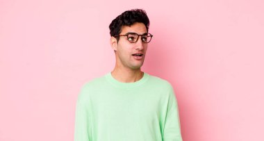 Yakışıklı İspanyol adam şok olmuş, mutlu, şaşkın ve şaşırmış hissediyor, ağzı açık bir şekilde yana bakıyor.