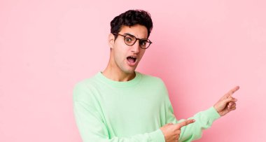 Yakışıklı İspanyol bir adam şaşkın ve şaşırmış hissediyor. Yandaki fotokopi alanını işaret ediyor. Şaşırmış ve ağzı açık bakıyor.