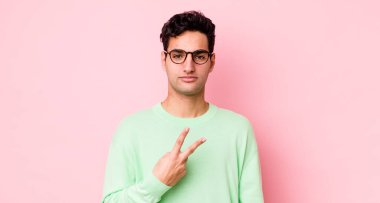 Yakışıklı İspanyol adam kendini mutlu, pozitif ve başarılı hissediyor. Göğsünde el yapımı V şekli var. Zafer ya da barış gösteriyor.