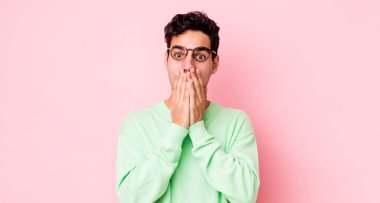 Yakışıklı İspanyol adam elleri ile ağzını kapatıyor, şok olmuş, şaşırmış bir ifadeyle, sır saklıyor ya da 