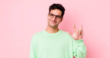 Yakışıklı İspanyol adam kendini mutlu, eğlenceli, kendinden emin, pozitif ve asi hissederek elle rock ya da heavy metal işareti yapıyor.