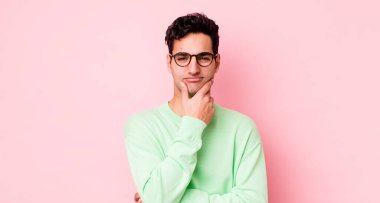 Yakışıklı İspanyol bir adam ciddi, düşünceli ve güvensiz görünüyor, bir kolu çapraz ve çene üzerinde, seçenekleri tartıyor