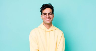 Yakışıklı İspanyol adam utangaç ve neşeli bir şekilde gülüyor, arkadaş canlısı ve olumlu ama güvensiz bir tavırla.