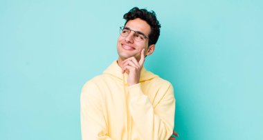 Yakışıklı İspanyol adam mutlu bir şekilde gülümsüyor ve hayal kuruyor ya da şüphe ediyor.