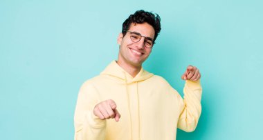 Yakışıklı İspanyol adam mutlu ve kendinden emin, kamerayı iki eliyle gösteriyor ve gülüyor, seni seçiyor.