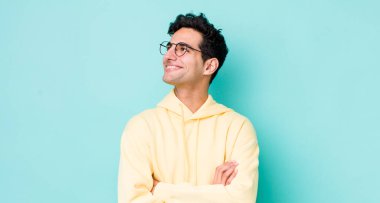 Yakışıklı İspanyol adam kendini mutlu, gururlu ve umutlu hissediyor, merak ediyor ya da düşünüyor, çapraz kollarla fotokopi çekmeye çalışıyor.