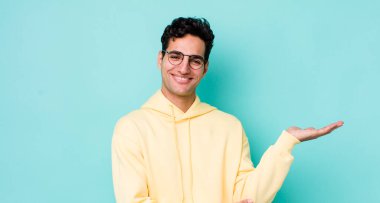 Yakışıklı İspanyol adam gururla ve güvenle gülümsüyor, mutlu ve tatmin olmuş hissediyor ve fotokopi alanında bir konsept gösteriyor.