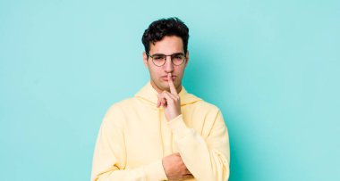 Yakışıklı İspanyol adam ciddi görünüyor ve parmaklarını dudaklarına bastırıp sessizlik ya da sessizlik talep ediyor, sır saklıyor.