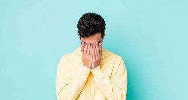 Yakışıklı İspanyol adam üzgün, hayal kırıklığına uğramış, gergin ve depresif, iki eliyle yüzünü kaplayan, ağlayan