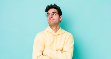 Yakışıklı İspanyol adam omuz silkiyor, kafası karışık ve emin değil, kolları bağlı ve şaşkın görünüyor.