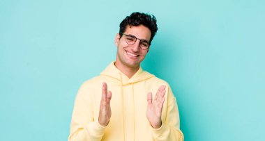 Yakışıklı İspanyol adam mutlu ve başarılı hissediyor, gülümsüyor ve alkışlıyor, alkışlarla tebrik ediyor.