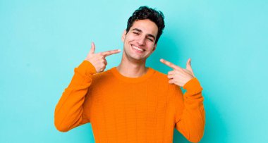 Yakışıklı İspanyol adam kendine güvenerek gülümsüyor. Geniş gülümseme, pozitif, rahat, tatmin olmuş tavır.