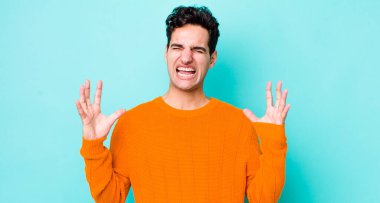 Yakışıklı İspanyol adam öfkeyle bağırıyor, stresli ve elleri havada neden ben diye bağırıyor.