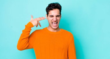 Yakışıklı İspanyol adam mutsuz ve stresli görünüyor, intihar jesti elle silah işareti yapıyor, kafasını işaret ediyor.