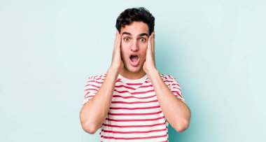 Yakışıklı İspanyol adam hoş olmayan bir şekilde şoka uğramış, korkmuş ya da endişeli, ağzı sonuna kadar açık ve iki kulağını da elleriyle kapatıyor.