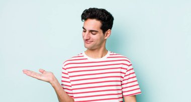 Yakışıklı İspanyol bir adam kendini mutlu hissediyor ve gülümsüyor. Elinde tuttuğu bir nesneye ya da konsepte bakıyor.