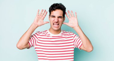 Yakışıklı İspanyol adam panik ya da öfke içinde bağırıyor, şok olmuş, korkmuş ya da öfkeli, elleri başının yanında.