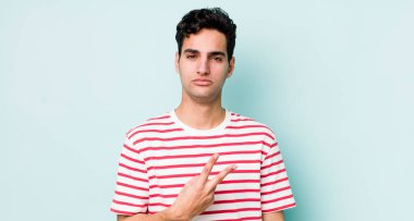 Yakışıklı İspanyol adam kendini mutlu, pozitif ve başarılı hissediyor. Göğsünde el yapımı V şekli var. Zafer ya da barış gösteriyor.