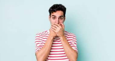 Yakışıklı İspanyol adam elleri ile ağzını kapatıyor, şok olmuş, şaşırmış bir ifadeyle, sır saklıyor ya da 