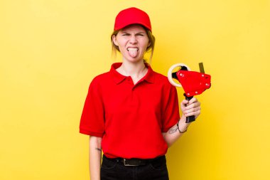 Kızıl saçlı güzel kadın iğrenmiş ve sinirlenmiş hissediyor ve dilini dışarı çıkarıyor. paketleyici kavramı