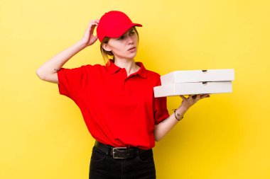 Kızıl saçlı güzel kadın mutlu bir şekilde gülümsüyor ve hayal kuruyor ya da şüphe ediyor. Pizza dağıtımı kavramı