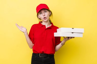 Kızıl saçlı, güzel bir kadın şaşırmış ve şok olmuş görünüyor. Çenesi düşmüş, elinde bir nesne var. Pizza dağıtımı kavramı
