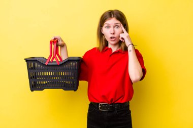 Kızıl saçlı güzel kadın şaşırmış görünüyor, yeni bir düşünce, fikir ya da konsept fark ediyor. Alışveriş sepeti konsepti