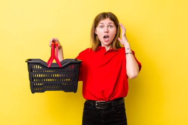 Kızıl saçlı güzel kadın ellerini havaya kaldırarak çığlık atıyor. Alışveriş sepeti konsepti