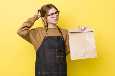 Kızıl saçlı güzel kadın mutlu bir şekilde gülümsüyor ve hayal kuruyor ya da şüphe ediyor. teslimat paket servis kavramı