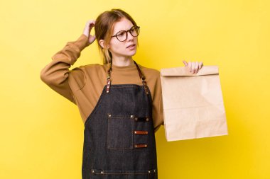 Kızıl saçlı güzel kadın şaşkın ve kafası karışık, kaşınan bir kafa hissediyor. teslimat paket servis kavramı