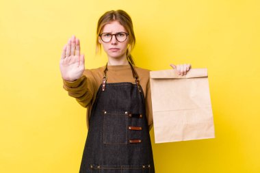 Kızıl saçlı güzel kadın ciddi görünüyor. Avuç içini gösteriyor. Durdurma hareketi yapıyor. teslimat paket servis kavramı
