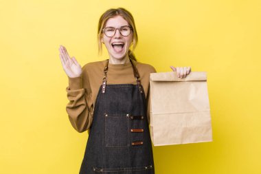 Kızıl saçlı güzel kadın kendini mutlu hissediyor ve inanılmaz bir şeye hayret ediyor. teslimat paket servis kavramı