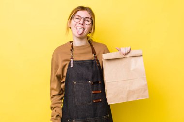 Kızıl saçlı, güzel, neşeli ve asi tavırlı, şaka yapan ve dilini dışarı çıkaran bir kadın. teslimat paket servis kavramı