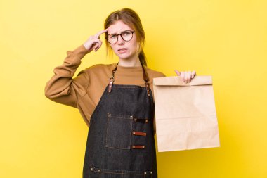 Kızıl saçlı güzel kadın kafası karışık ve şaşkın hissediyor, deli olduğunu gösteriyor. teslimat paket servis kavramı