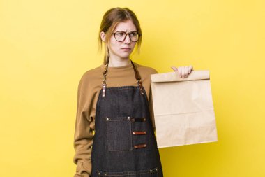 Kızıl saçlı, güzel bir kadın üzgün, üzgün ya da kızgın ve yana bakıyor. teslimat paket servis kavramı