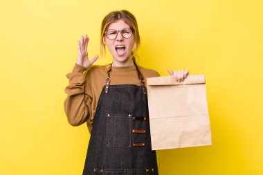 Kızıl saçlı güzel kadın ellerini havaya kaldırarak çığlık atıyor. teslimat paket servis kavramı